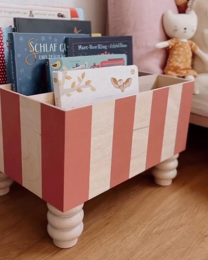 Coral and cream striped Moppe storage box from @kruthdesign holding children's books and toys.