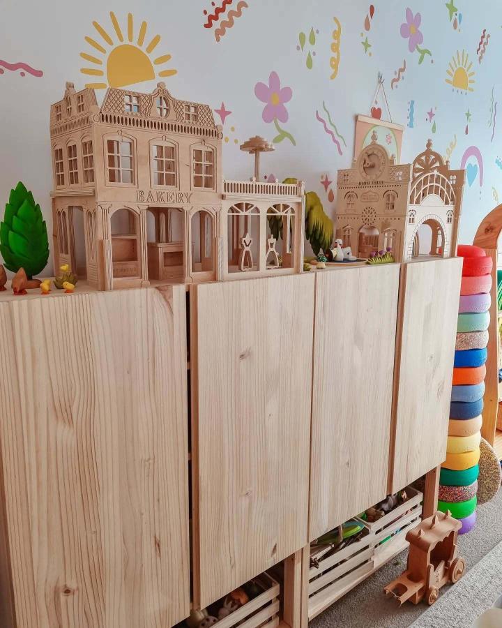 Natural pine Ivar cabinets from @the_gorman_lane with wooden dollhouses and colorful wall decals above.