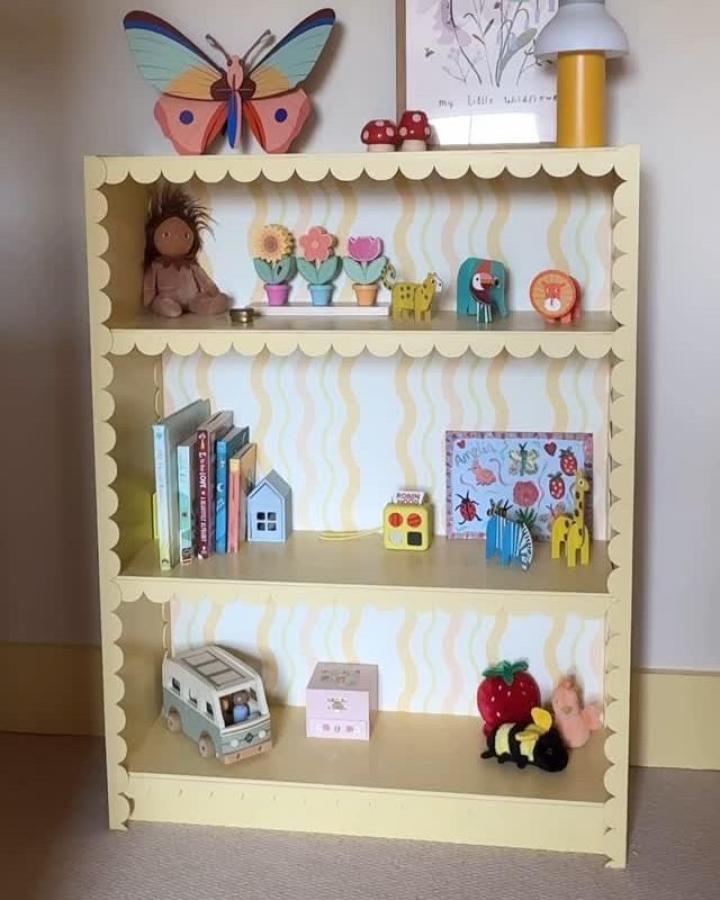 Yellow scalloped Billy bookcase from @_itstartedwithacushion. Chevron backing holds colorful toys and books.