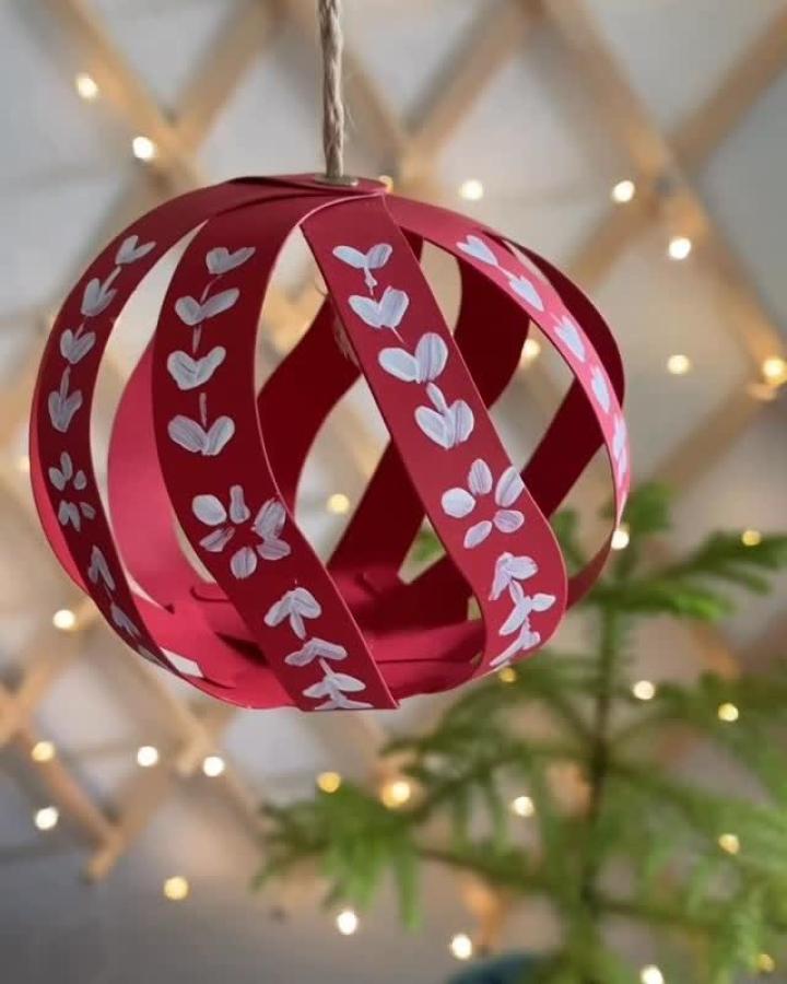 Red paper sphere ornament from @astrids_werkstatt decorated with white hand painted heart details.
