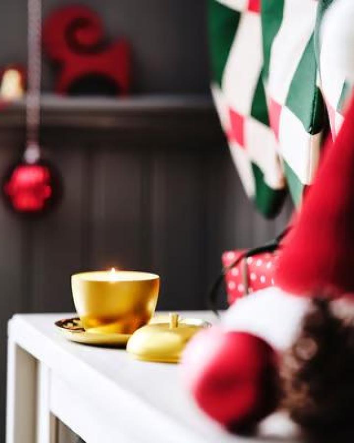 Golden apple-shaped scented candle from Ikea. Metal tin with festive ornaments nearby.