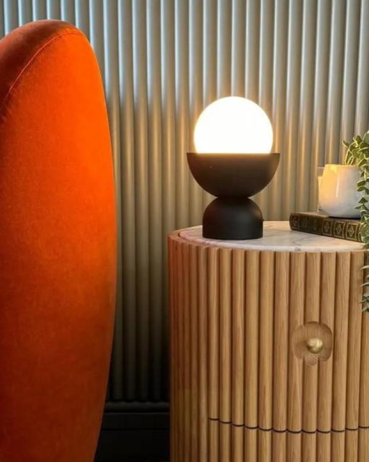 Black painted Ikea lamp on fluted wood cabinet from @crack_thes_shutters. Glowing globe with sculptural geometric base.