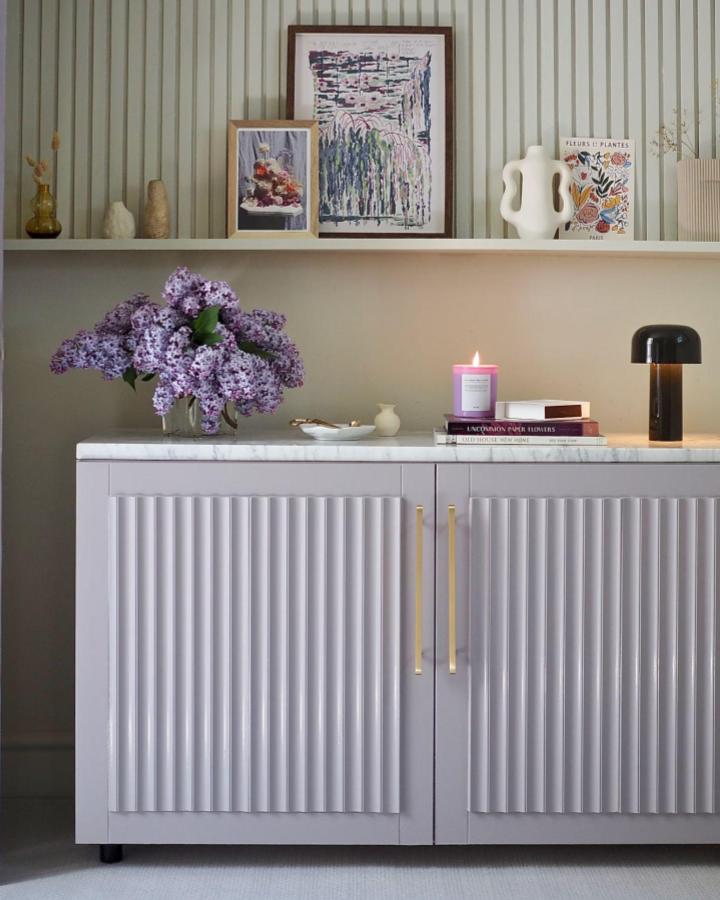 Lavender-gray fluted Besta cabinet from Melanie Lissack. Brass hardware and marble countertop styling.
