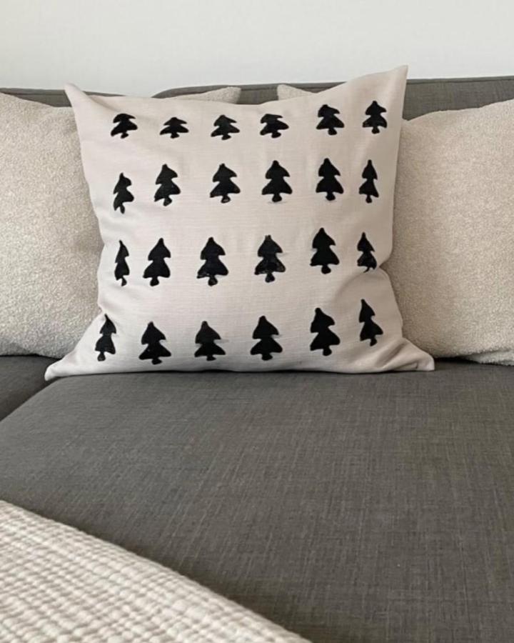 Black potato-printed Christmas trees on beige Majbraken cushion cover from @_laura_living. Minimalist Scandi holiday styling.