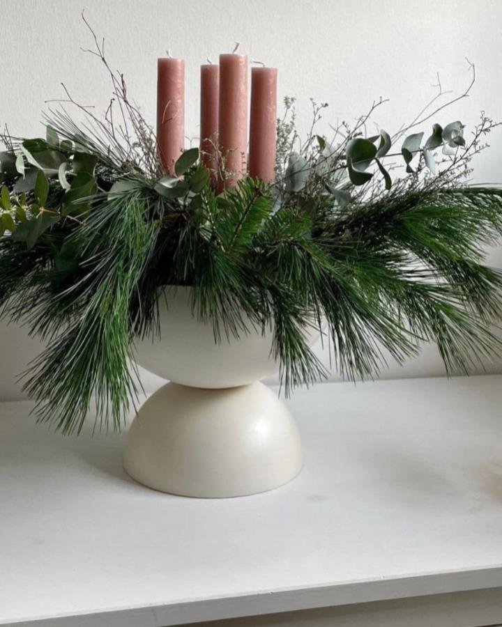 White stacked bowl centerpiece from @_laura_living with dusty pink candles and lush winter greenery arrangement.