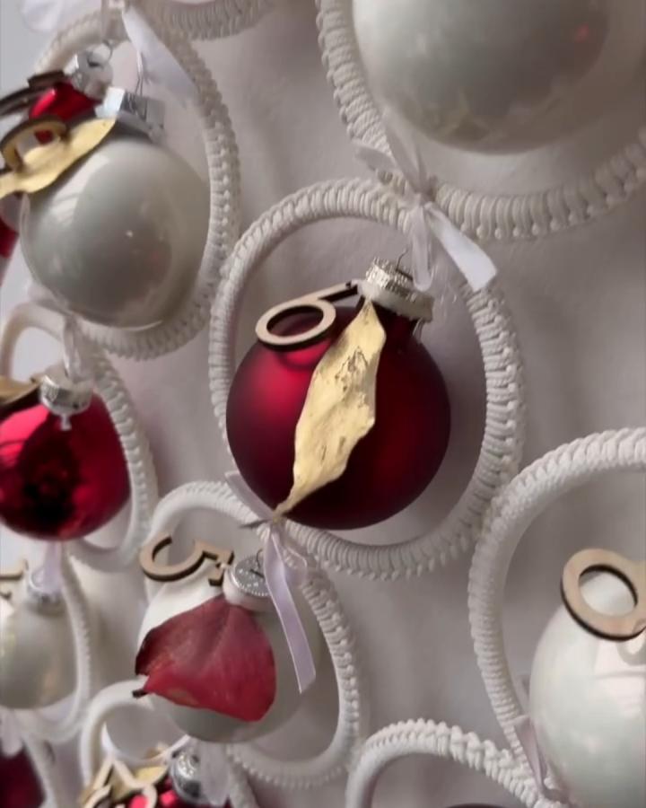 White rope hanger advent calendar from @menawox displaying burgundy and silver ornaments with wooden number tags.