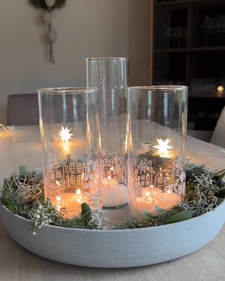 Clear glass cylinder vases from @b__living with chalk pen winter village illustrations and candlelight glow.
