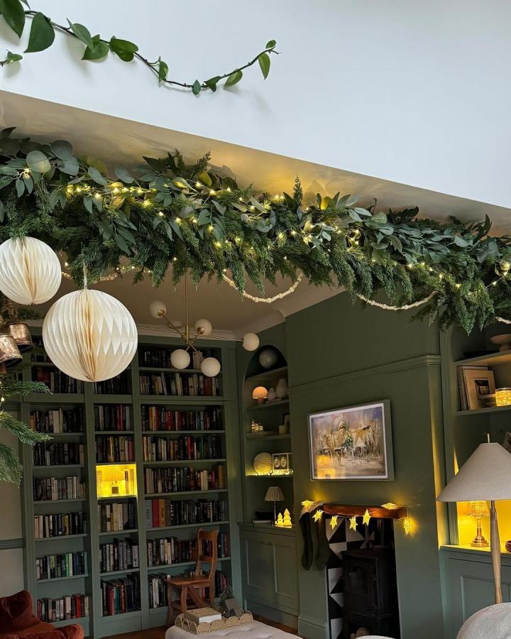 Lush garland with fairy lights on wooden pole from @crack_the_shutters. Eucalyptus and pine branches cascade overhead.