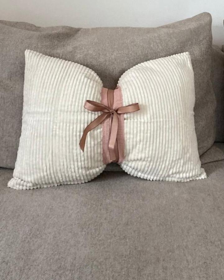 Cream ribbed cushion from @_laura_living with pink bow, showcasing ikea christmas decoration hacks & ideas through simple ribbon styling.