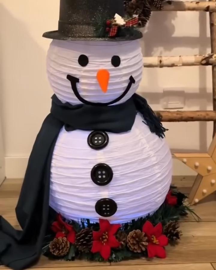 White paper lantern snowman from @inspo.lana with black hat and green scarf decoration.