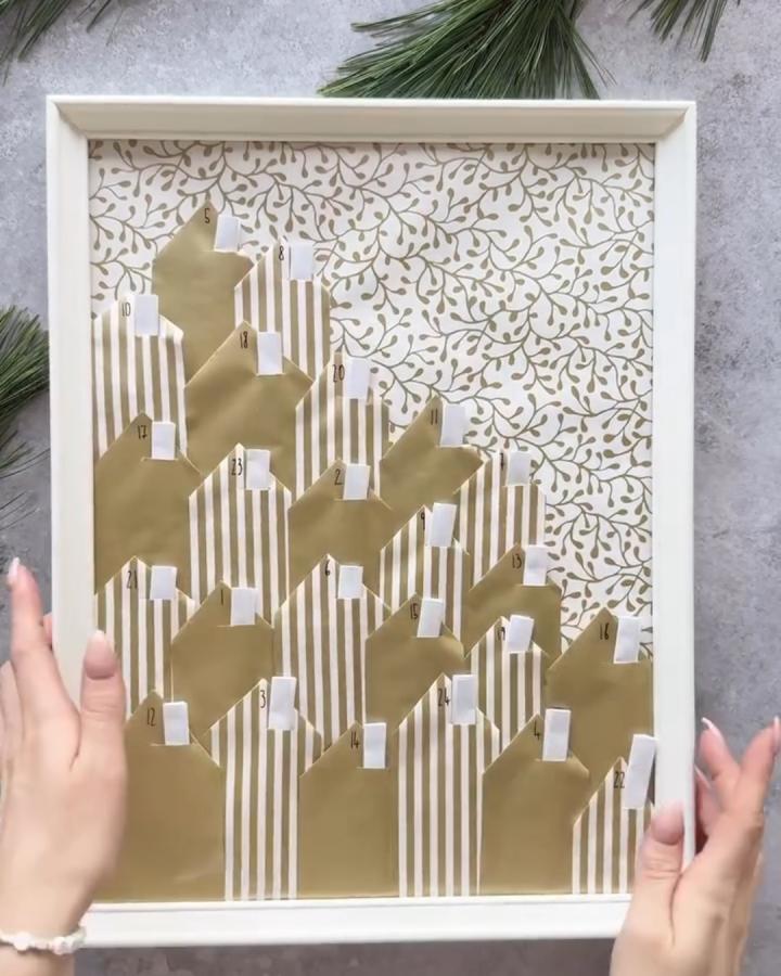 Framed advent calendar showcasing ikea christmas decoration hacks & ideas from @menawox. Gold pockets on striped botanical backdrop.