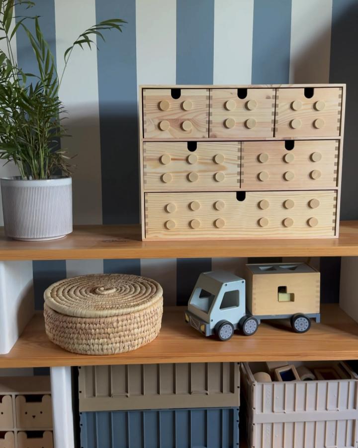 Natural wood drawer unit with circular stud details from @our.home.atno50. Styled on open shelving with toys.