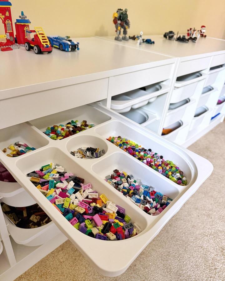 White compartment trays inside drawer units from @megan_marie_organizing. Bricks sorted by vibrant colors.