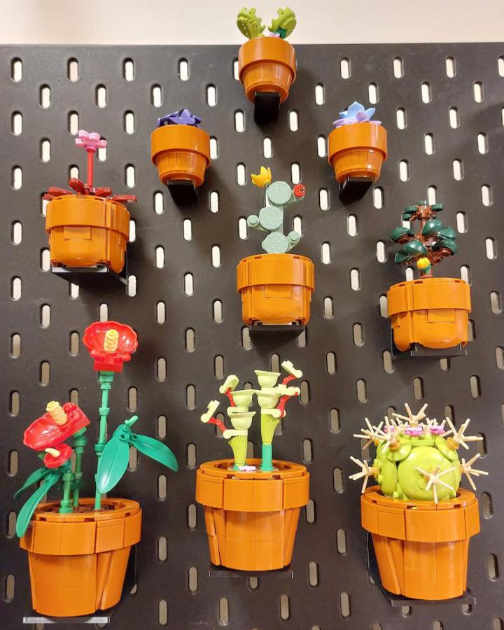 Gray pegboard display from MaGo3dPL with orange Lego botanical pots mounted vertically using custom supports.