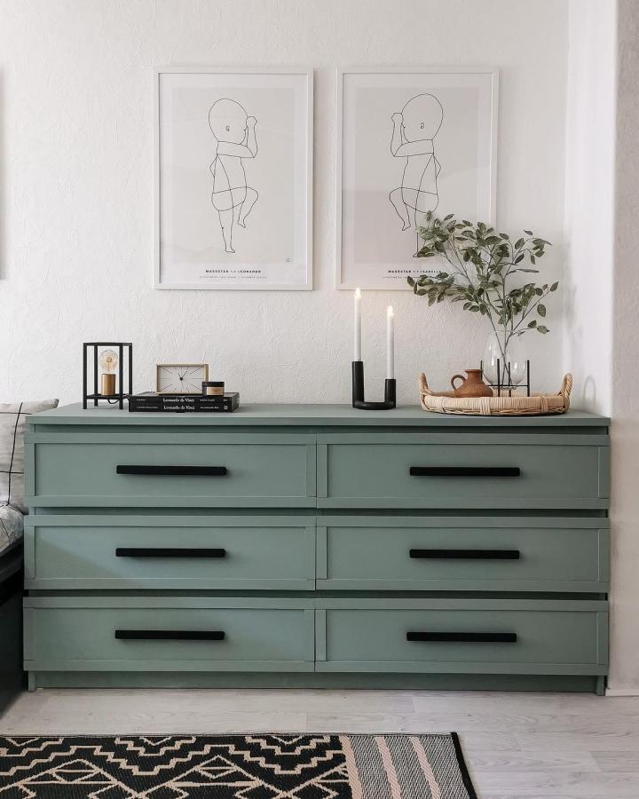 sage green painted dresser in a modern living room from @leoxbella. Minimalist styling with black handles and natural accents.