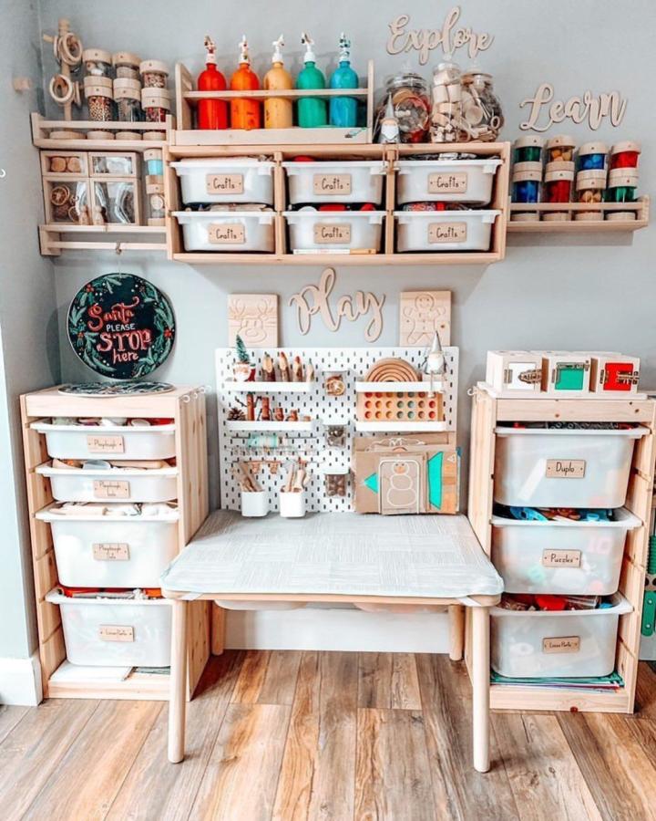 Natural wood craft station with white storage bins from @kiddiepinnie. Pegboard backdrop organizes supplies.