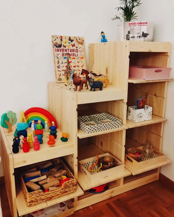 Natural wood ikea montessori hacks & ideas storage system from @liberi_di_crescere with tiered shelves and colorful toys.