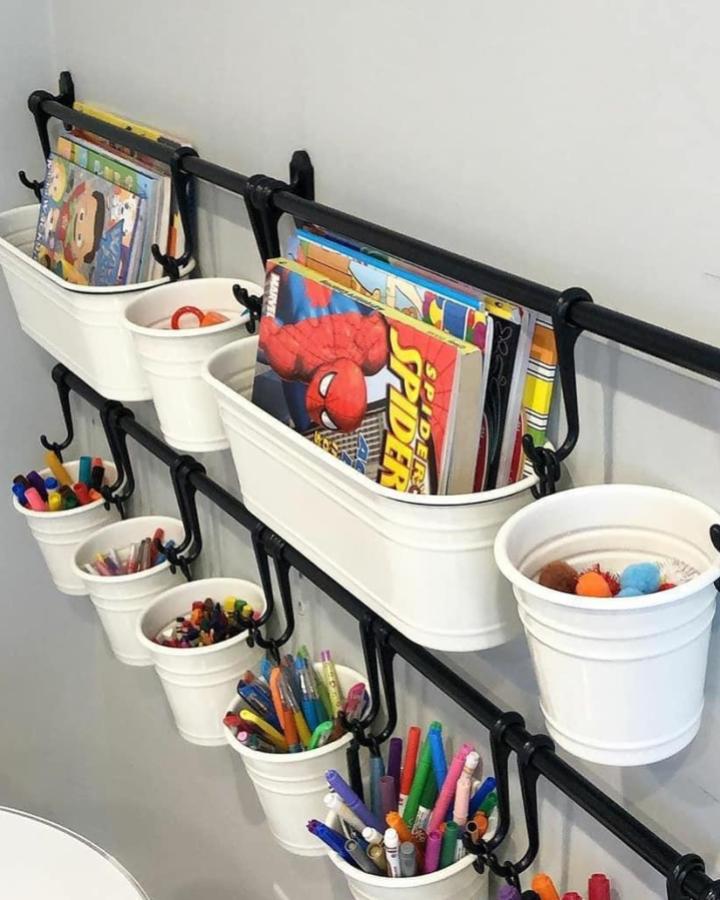 Black and white wall-mounted ikea playroom storage hacks & ideas from @organizedandsimplified4u with buckets holding art supplies and books.