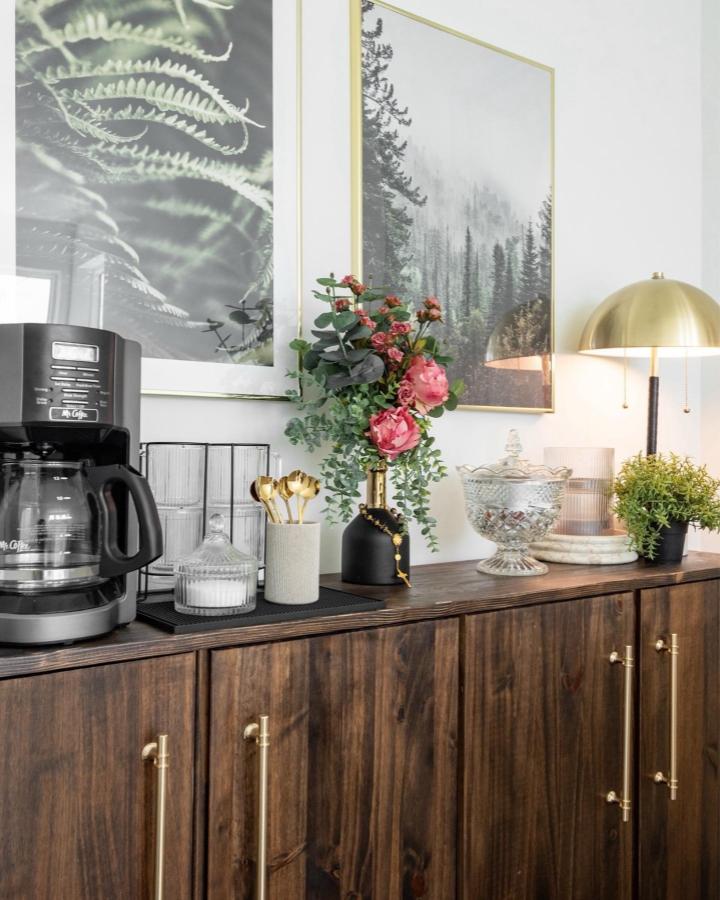 dark wood cabinet with brass handles in kitchen setting from @iwanderincolor. Accented by flowers, coffee maker, and gold lamp creating warm style ikea storage hacks & ideas