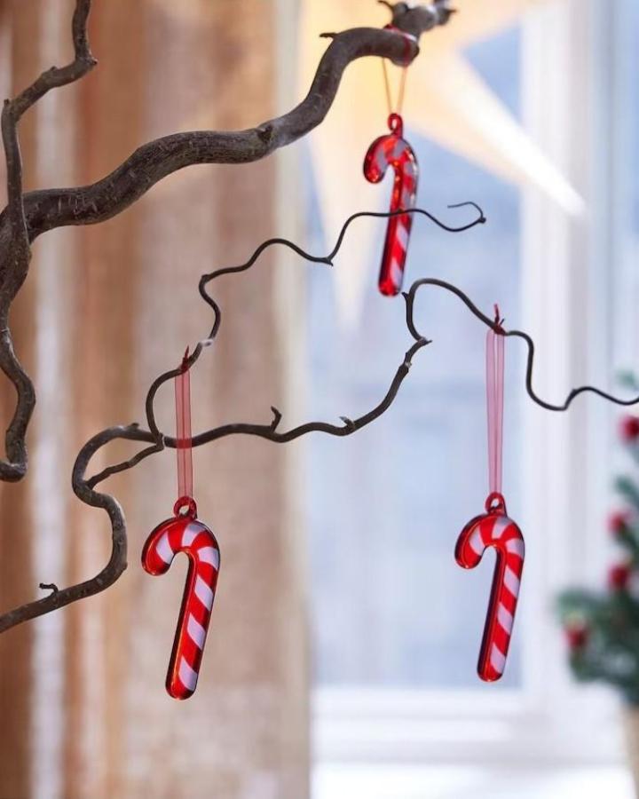 Red and white striped glass candy cane ornaments showcasing ikea vinterfint hacks & ideas on natural branch display.