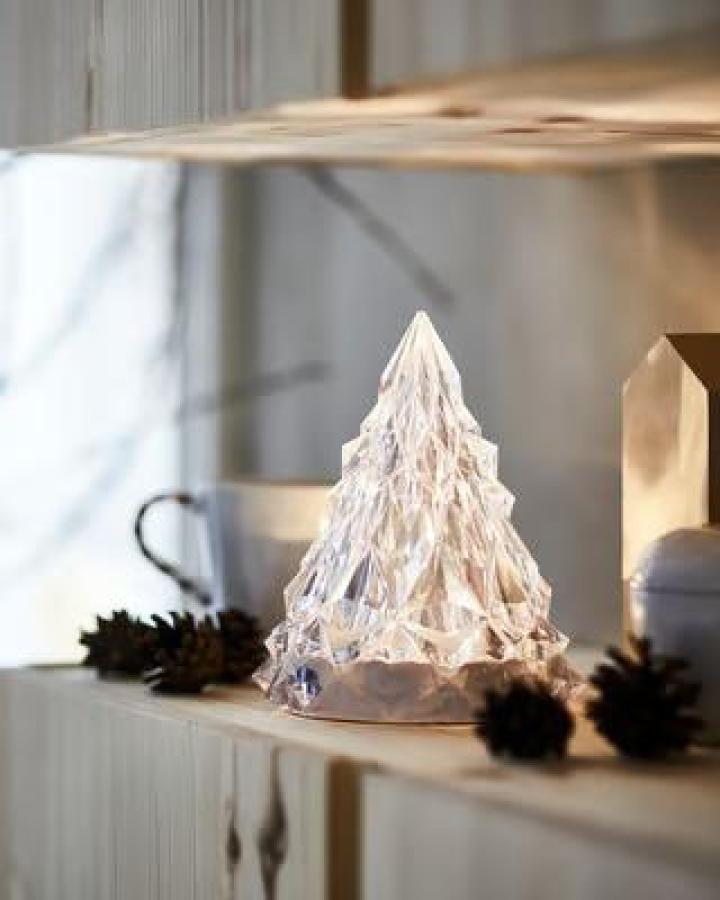 Clear acrylic LED tree decoration from Ikea. Displayed on white mantel with pinecones and warm lighting.