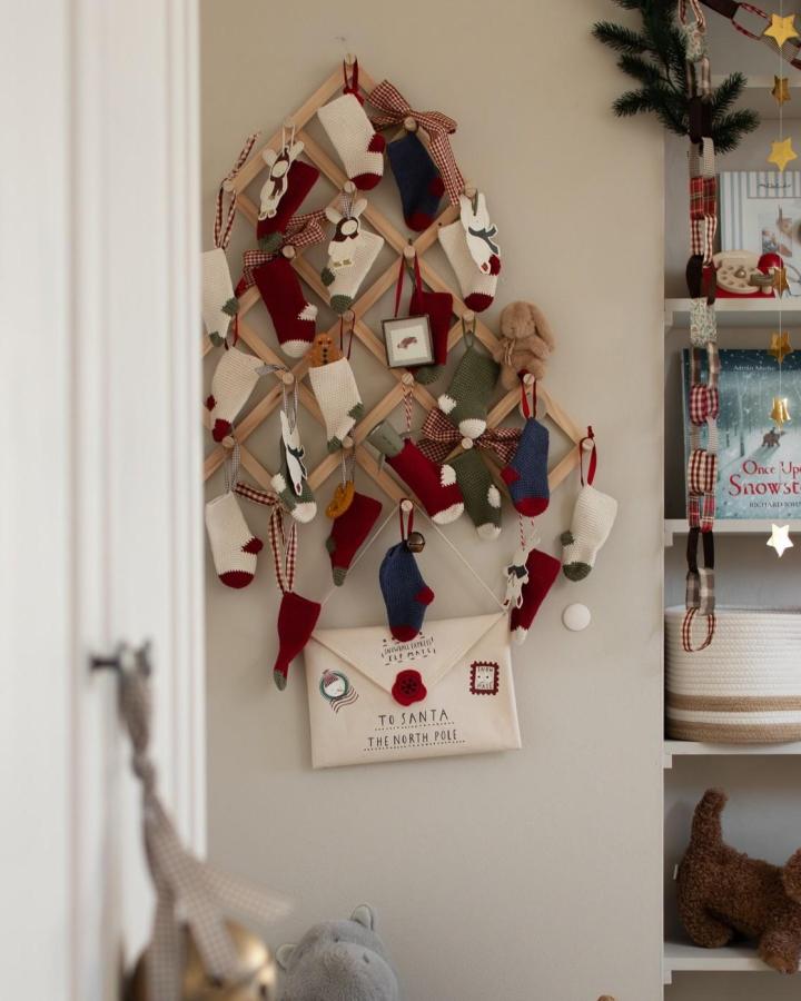 Wooden dowel tree with colorful mini stockings from @veronikakletenska. Geometric advent calendar display.