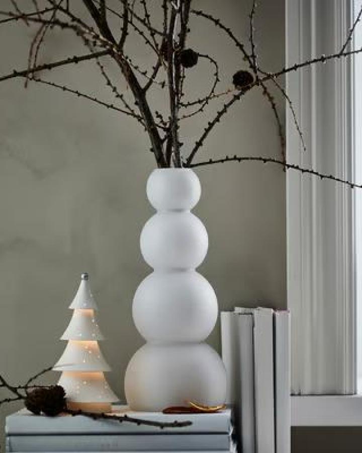 Frosted white stacked sphere vase from Ikea filled with dark winter branches on neutral surface.