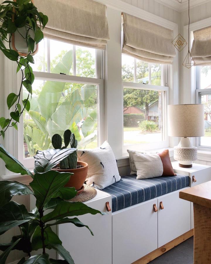 White built-in window bench from @thathomebirdlife with navy striped cushion and leather cabinet pulls.
