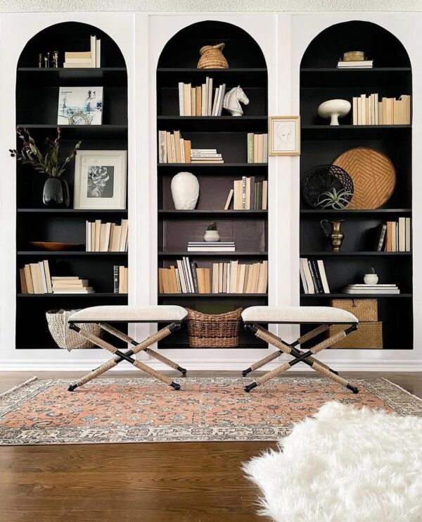 Black arched IKEA Billy bookcase hack from @ladieswhodiy. White trim frames styled shelves.