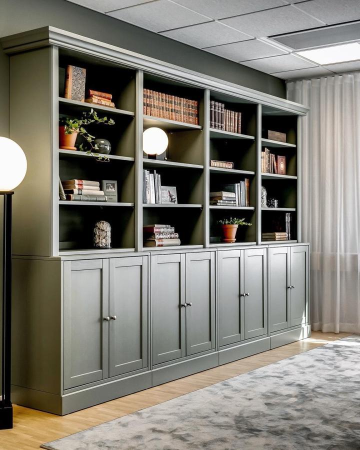 muted olive green classic style bookcase from @sparrow_and_weston. closed cabinets with open shelves and crown molding