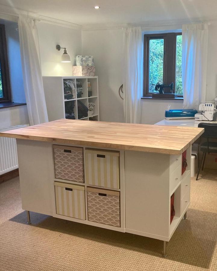 white Kallax craft table with butcher block top and patterned fabric bins from @theintrovertedsewist ikea kallax craft table hacks