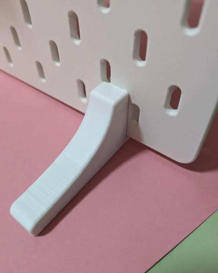 White plastic peg hook on Ikea Skadis pegboard craft room hacks with pink and green background from RosebyDesignAndPrint minimalist storage solution