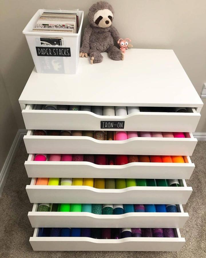 white Ikea Alex drawers with colorful Cricut vinyl rolls organized by type and color from @smartfundiy in a cozy craft space