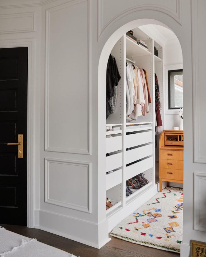 White built-in pax closet in arched alcove from @alannadunn simple chic organized storage with vintage wood dresser next to it