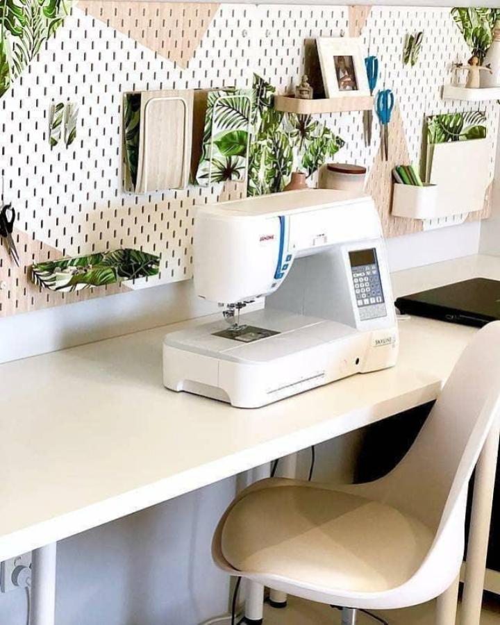 White Linnmon desk and Skadis pegboard with tropical leaf accents in a sewing space from @smartfundiy ikea sewing room hacks & ideas.
