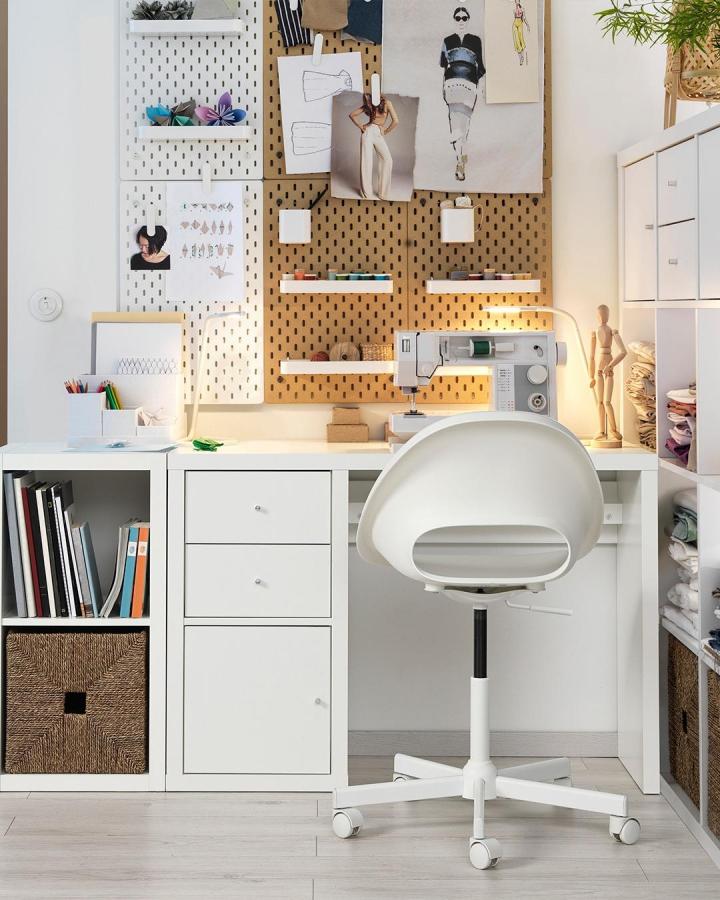 White modern Ikea Kallax desk and shelves with pegboard wall organization and sewing accessories in a cozy craft space from @ikea.