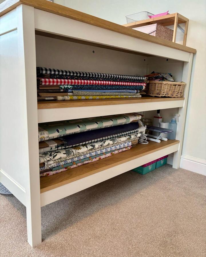 White and natural wood Ikea Tornviken island shelves storing patterned fabric bolts from @bluebellcoast for ikea sewing room hacks & ideas.