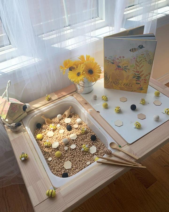 Natural wood sensory bin play table from @lostatseaandco featuring bees and honeycomb shapes in ikea flisat table hacks & ideas.