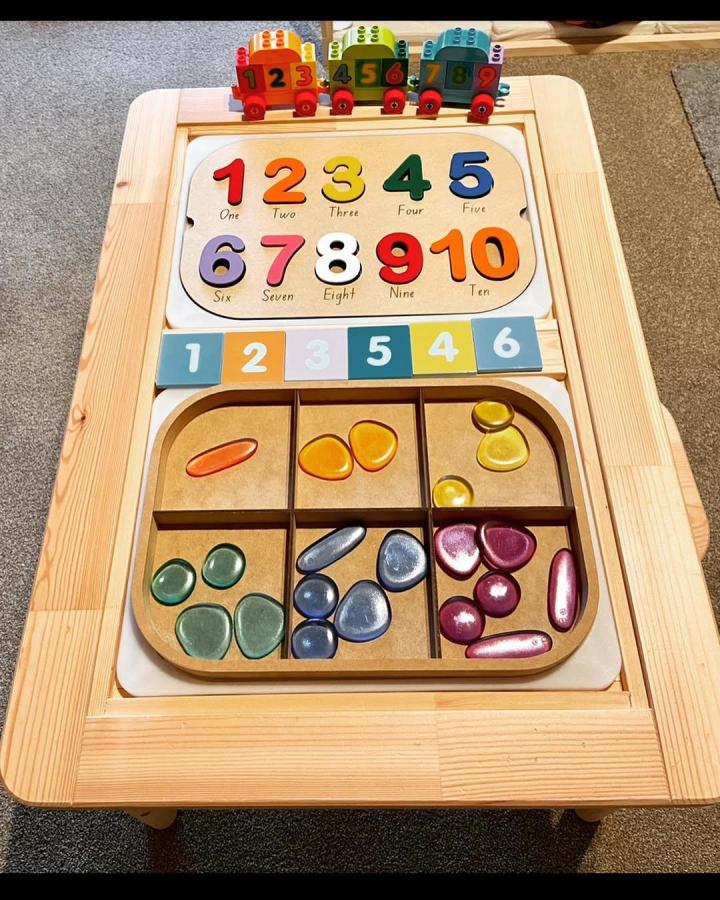 Natural pine Ikea Flisat table hacks & ideas by @learning.with.jo featuring colorful wooden number puzzles and sorting trays.