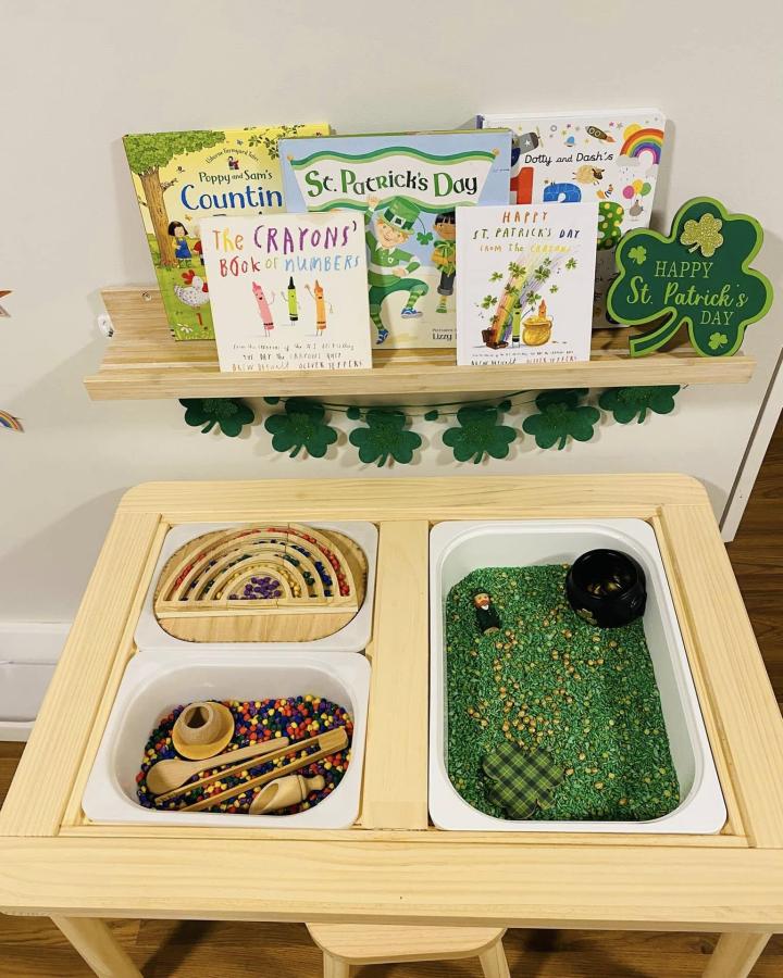 Natural pine sensory play table with colorful bins and wall shelf from Christina Ann. Includes beads, textured rice, and themed decor.