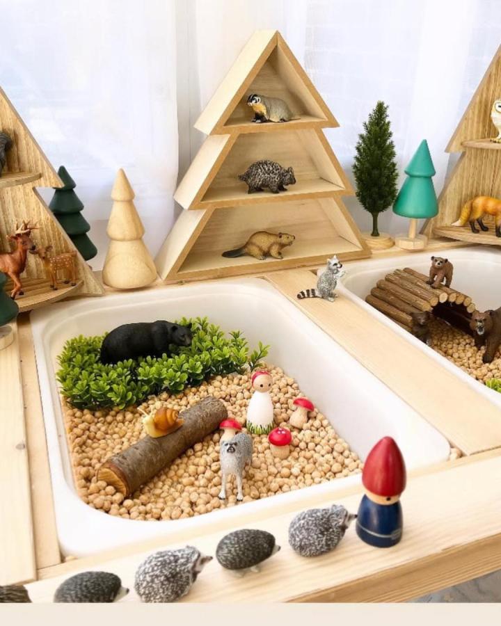 Wooden woodland scene with mini trees and animals on Ikea Flisat table by @mybigworldplayscapes creating a nature play area.