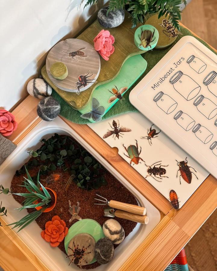Green and natural wood Ikea Flisat table with bug-themed decor and gardening play, designed by @the_new_forest_nest.