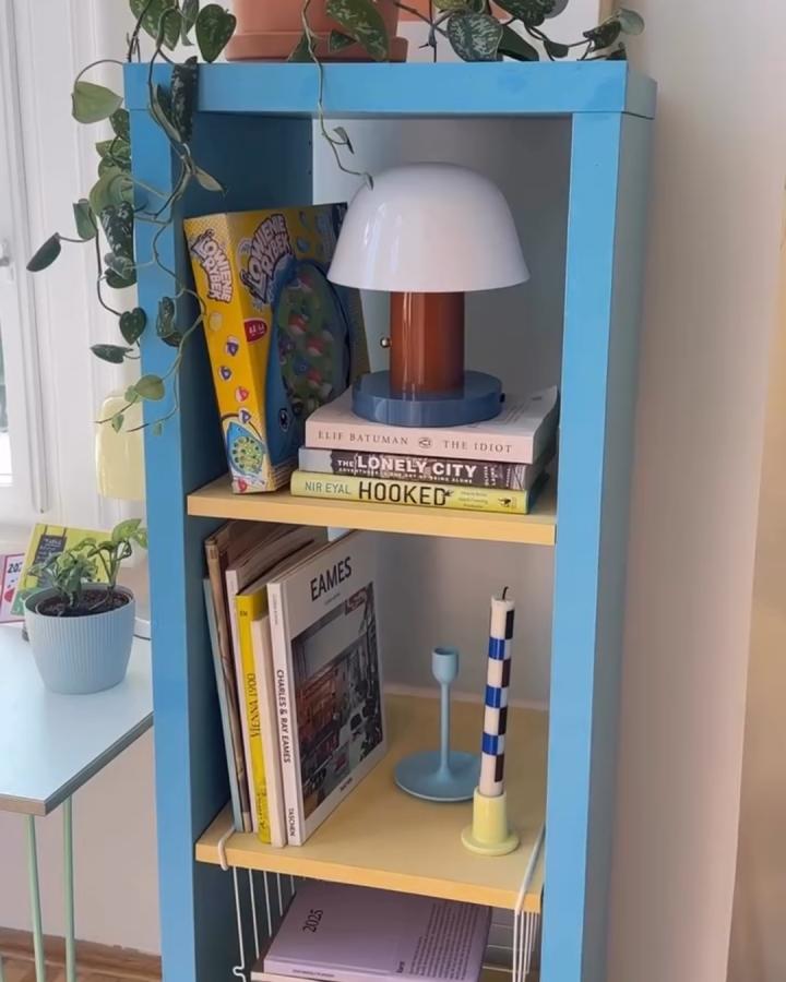 Bright blue and soft yellow ikea kallax makeover ideas shelving unit with books, lamp, and plants from @mengmengliving.
