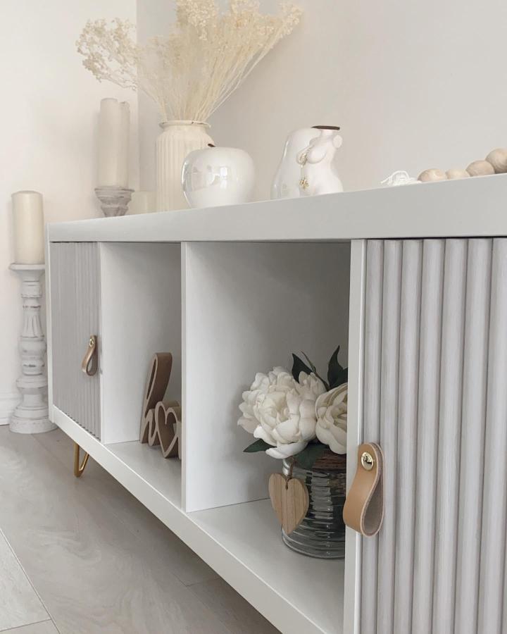 Light gray ribbed doors and leather strap handles on ikea kallax makeover ideas by @elocin_home with simple floral and wood accents.