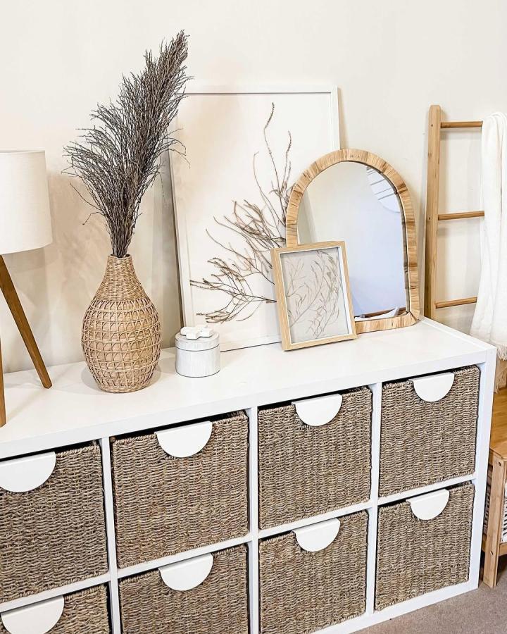 A white Ikea Kallax with woven baskets and BEGRIPA handles styled with natural accents by @crazy.beautiful.living