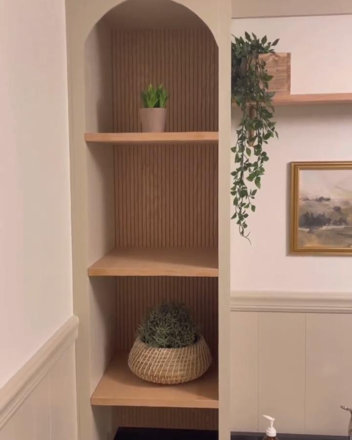 Natural wood slat backing on Ikea Kallax shelves from @roomforrevival with woven basket and potted plants.