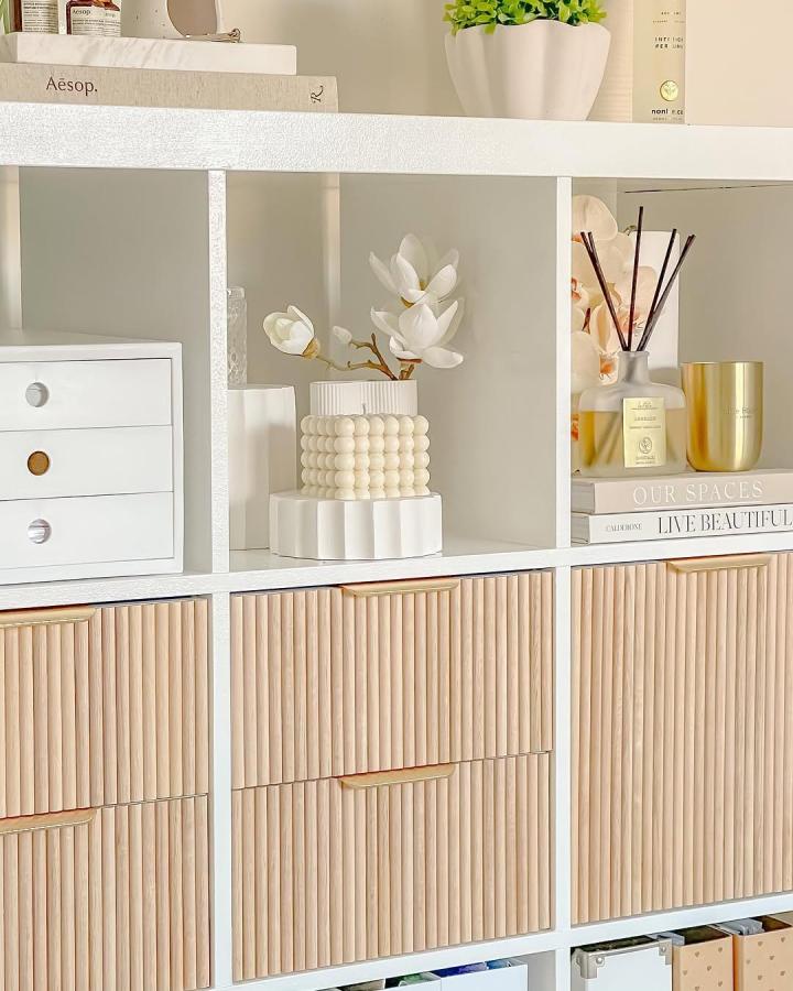Light natural wood textured panel Ikea Kallax storage with white cubes and decorative ceramics from @stylingmyinterior. Stylish and tactile ikea kallax styling ideas.