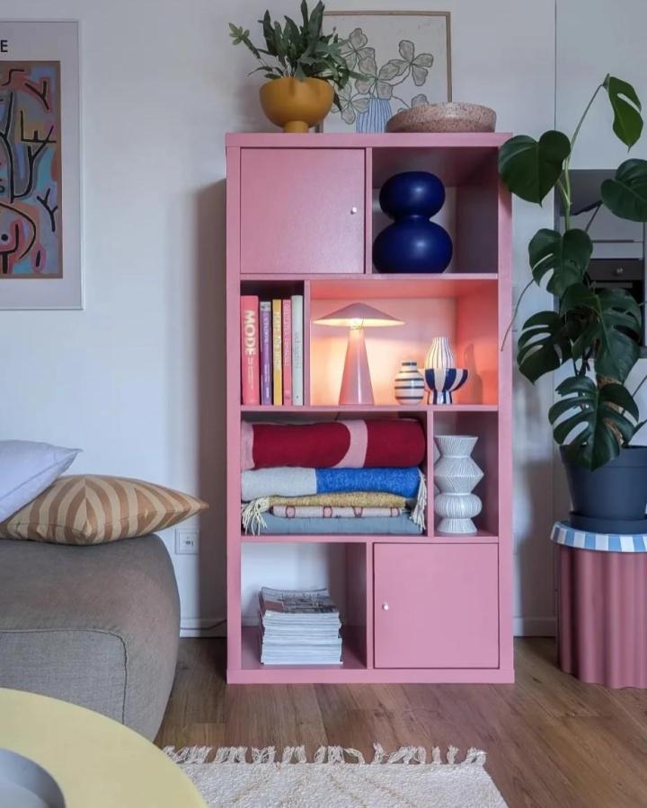 Pink painted Ikea Kallax shelving unit styled with colorful ceramics, textiles, and plants from @terrazzo.konfetti ikea kallax styling ideas
