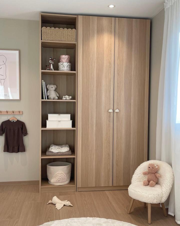 Light oak veneer ikea kids wardrobe ideas from @nordisk.heim featuring cloud knobs and open shelving with soft toys and baskets.