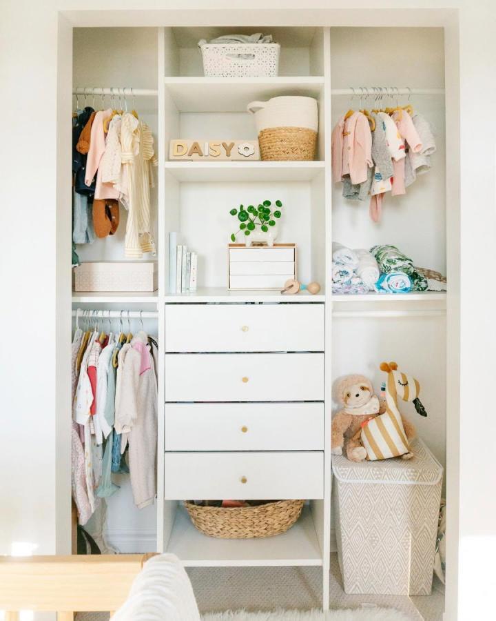 white painted PAX wardrobe with double closet rods and woven baskets from @lavender_julep ikea kids wardrobe ideas with soft pastel clothing and playful wooden drawer knobs